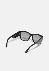 Ochelari de soare dreptunghiulari negri cu lentile gri, finisaj lucios și marcaj puternic "vogue" pe templul din dreapta. Design cu cadru din plastic solid.