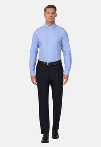 Jasnoniebieska koszula w paski z rozłożystym kołnierzem, zapinana na guziki z przodu, z długimi rękawami, w połączeniu z ciemnogranatowymi spodniami i czarnymi butami.