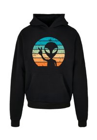 Schwarzer Hoodie mit einem zentralen Grafikdesign eines Cartoon-Aliens, der ein Peace-Zeichen macht, vor einem farbverlaufenden Kreis aus blauen und orangefarbenen Streifen.