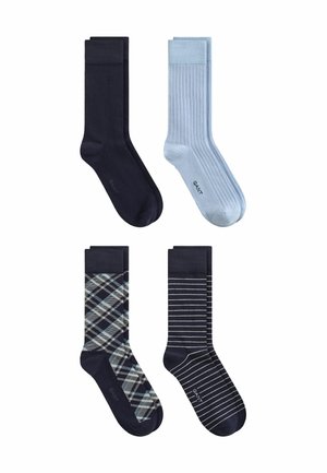 Quatre paires de chaussettes pour hommes en noir, bleu clair, noir à carreaux et noir avec des rayures blanches, disposées en deux rangées sur un fond blanc.