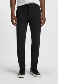 Czarne spodnie wykonane z lekkiego materiału, charakteryzuj�ące się prostym fasonem, kieszeniami z przodu, zapięciem na guzik oraz subtelną teksturą. W połączeniu z czarnymi trampkami.