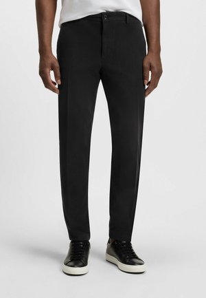 Black trousers made of lightweight fabric, featuring a straight design, front pockets, a button closure, and subtle texture. Paired with black sneakers.