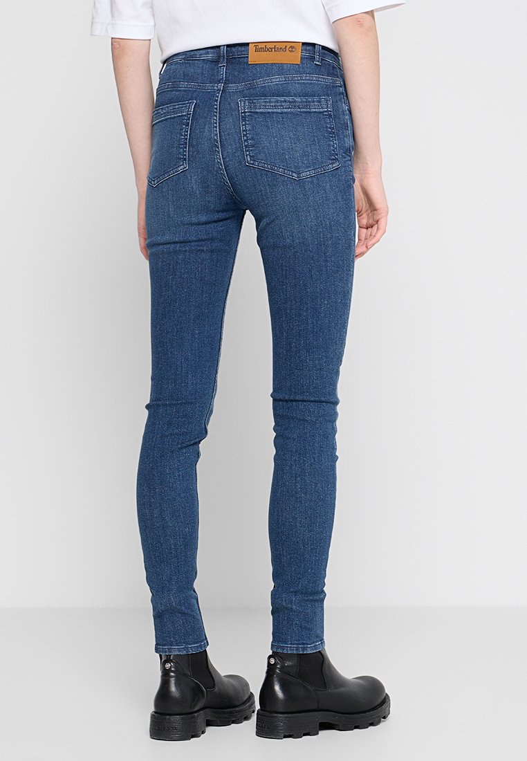 Chude dżinsy w kolorze niebieskim wykonane z denimu, z wysokim stanem, tylnymi kieszeniami i skórzaną metką Timberland na pasku.