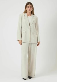 Lichtgekleurde gestreepte pakken set met een op maat gemaakte blazer met notched lapels en een wijdvallende broek. Gelaagd stof met een gladde afwerking.