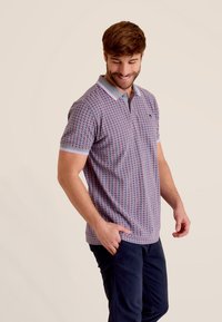 Korte mouwen polo in een roze en blauwe geometrische patroon, met een lichtgrijze kraag en contrasterende knoopsluiting. Katoenen stof, regular fit.