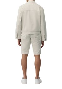 Lichtbeige spijkerjack en bijpassende shorts, beide met een gestructureerde afwerking. Eenvoudig ontwerp met minimale hardware en een casual pasvorm.