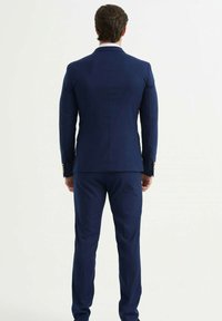 Costume bleu marine, composé d'une veste à un bouton avec une texture lisse et une coupe ajustée. Détails de boutons sur les manches, pantalon assorti.