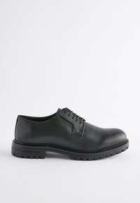Chaussure noire en cuir à lacets avec un bout arrondi, une tige texturée et une semelle en caoutchouc crantée. Présente des coutures minimales et une finition lisse.