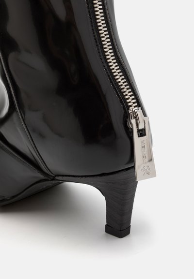 Stivale alla caviglia in pelle verniciata nera con cerniera argentata di lato e tacco sottile, texturizzato e nero. Presenta una finitura elegante e lucida.