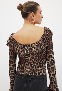 Dierenprint top met lange mouwen, gerimpelde halslijn en een getailleerd ontwerp. De stof heeft een bruin en zwart luipaardpatroon.