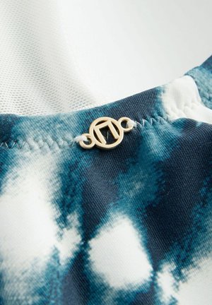 Kék és fehér árnyalatú batikolt anyag, arany színű fémrészletekkel. Az anyag sima tapintású, látható varrási részletekkel.