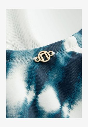 Kék és fehér árnyalatú batikolt anyag, arany színű fémrészletekkel. Az anyag sima tapintású, látható varrási részletekkel.