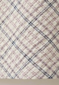 Tissu beige avec un motif quadrillé texturé avec des lignes croisées à carreaux grises et violet clair.