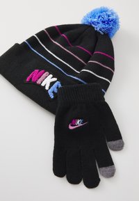 Căciulă neagră din tricot cu pompon albastru și dungi multicolore; mănuși asortate cu vârfuri negre și gri. Include sigla Nike brodată în culori vibrante.