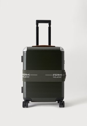 Valise rigide vert foncé à coque striée, avec une poignée déployée, quatre roulettes et une sangle siglée FPM Milano.