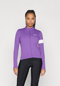 Jersey de ciclismo de manga longa roxa com fecho na frente, detalhe branco na manga e tecido suave e elástico. Usado sobre calções de ciclismo pretos.