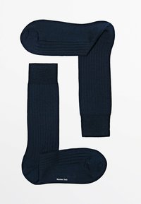 Paar dunkelblaue, gerippte Kniestrümpfe, flach in L-Form auf weißem Hintergrund ausgelegt, mit Markennamen auf der Sohle eines Strumpfs.