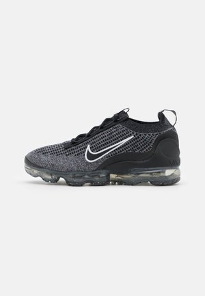 Schwarzer und grauer Nike Vapormax-Schuh mit weißem Swoosh-Logo und transparenter luftgepolsterter Sohle, von der Seite auf weißem Hintergrund gezeigt.