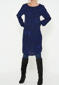 Navy blue tunic dress with long sleeves, featuring a floral pattern, paired with black knee-high boots made of suede-like material.