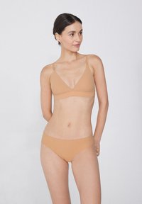 Beige Bralette und passende Unterhose, aus glattem Stoff gefertigt. Der Bralette hat dünne Träger und eine dreieckige Form. Einfaches, minimalistisches Design.