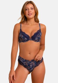 Ensemble de lingerie en dentelle navy avec des motifs floraux, des bretelles réglables et une bordure délicate. Le soutien-gorge a un support en armature, tandis que le string présente un bord festonné.