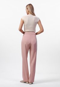 Lichtbeige getailleerde top met korte mouwen, gecombineerd met hooglopende, losse roze broeken. Gladde stof, gemiddelde glans en minimalistisch ontwerp.