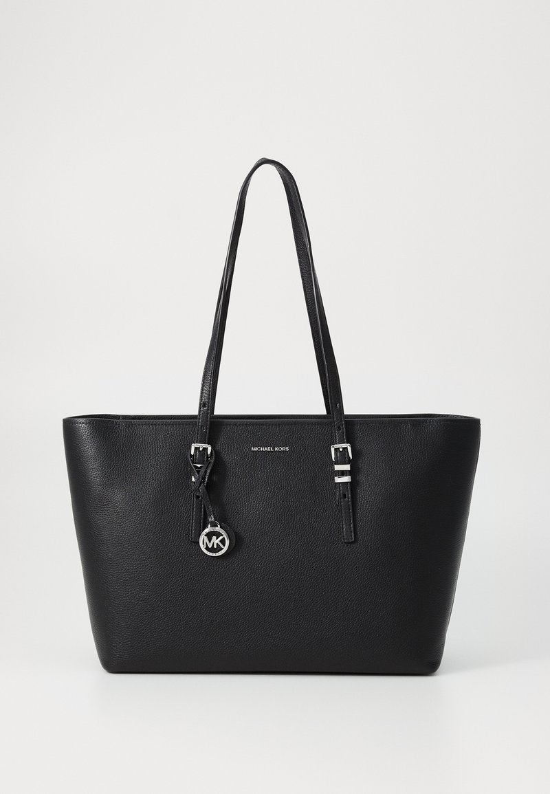 Sac cabas en cuir noir avec longues anses, détails de boucles argentées, logo Michael Kors et pendentif rond MK suspendu à une anse.