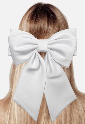 White satin bow positioned at the back of long, straight hair, featuring wide, flowing tails and a central knot for secure fastening.