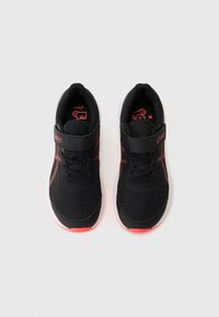 Baskets de sport noires en matériau en mesh, avec des accents rouges, une sangle à boucle et une semelle intermédiaire blanche. Design léger et respirant.