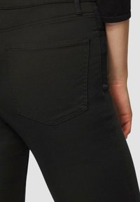 Zwarte denim jeans met een aansluitend ontwerp, een gladde textuur en een achterzak met een subtiele, schuine stiknaad.