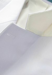 White fabric of a tailored shirt collar with a smooth texture and a contrasting white inner lining, showcasing neat stitching details.