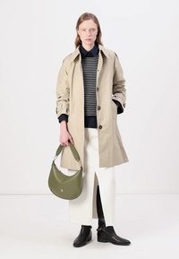 Beige trenčkot s knoflíkovým zapínáním, přes námořnický pruhovaný svetr, spárovaný s bílou sukní s bočním rozparkem a černými kotníkovými botami. Zelená kabelka.