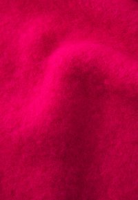 Tessuto di feltro rosa brillante con una morbida texture simile alla lana, caratterizzato da una superficie leggermente irregolare che mette in risalto il suo calore e la sua vivacità.