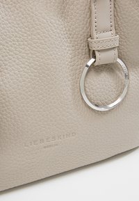 Beige texturovaná kožená taška se šitými popruhy a stříbrným kovovým kroužkem s embosovaným logem "Liebeskind Berlin".