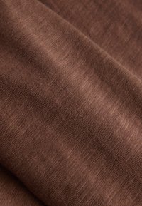 Tissu marron doux avec une texture tricotée fine et un motif chiné subtil, plié pour montrer des plis doux.