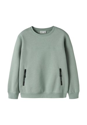 Sweat-shirt vert doux à col rond avec manches longues et deux poches verticales zippées à l'avant avec curseurs de fermeture éclair noirs.