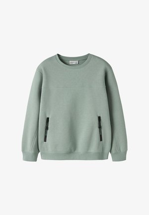 Sweat-shirt vert doux à col rond avec manches longues et deux poches verticales zippées à l'avant avec curseurs de fermeture éclair noirs.