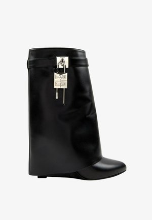 Botte compensée en cuir noir mi-mollet avec un cadenas géométrique argenté et un détail de clé près du bord supérieur.