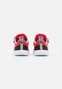 Scarpe sportive rosse e nere con tomaia in rete, collo imbottito e suola in gomma bianca con dettagli a trama. Cinturino regolabile in velcro.
