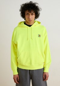 Neon yellow hooded sweatshirt in cotton blend with front pocket, drawstrings, and a small logo patch on the left chest.