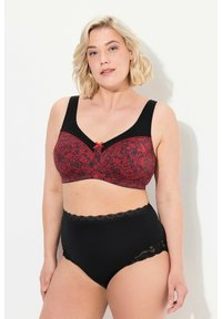 Schwarzer und roter BH mit Spitzenakzenten, der ein florales Design aufweist. Dicke Träger und eine Schleifen-Applikation in der Mitte. Hoch geschnittene schwarze Slips mit Spitzenrand.