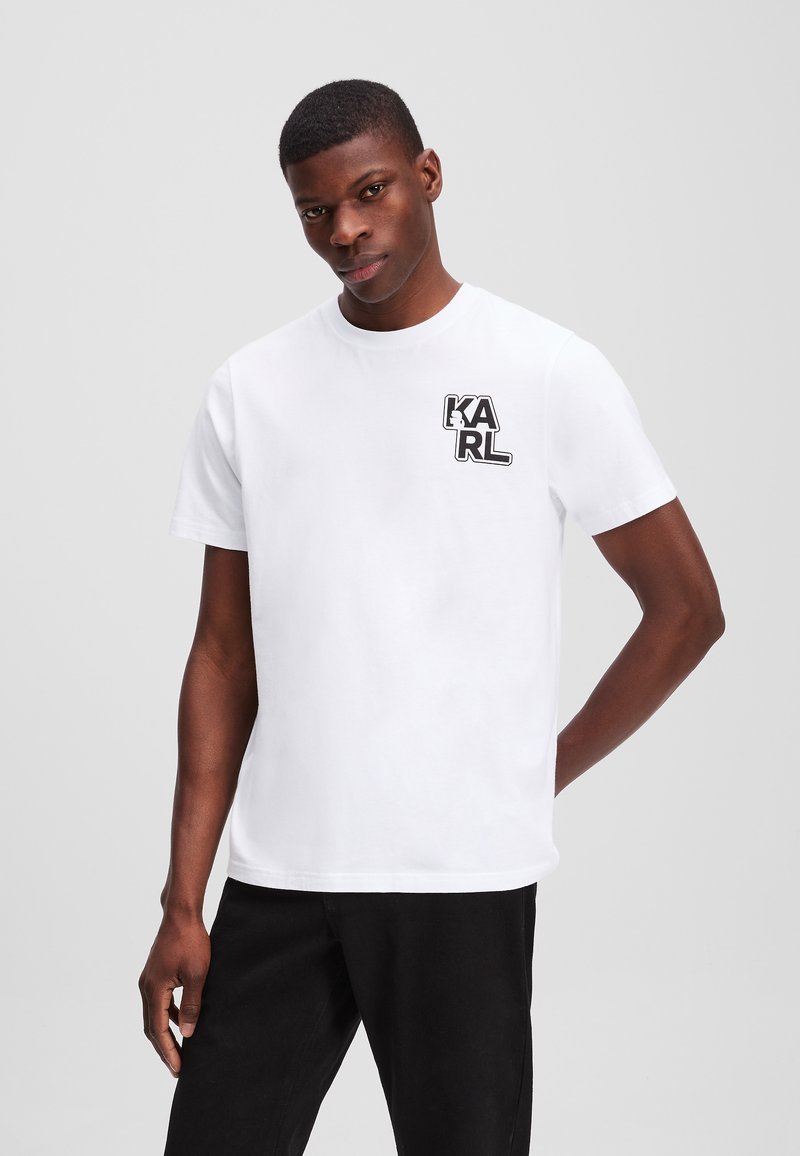 Witte katoenen t-shirt met een zwart grafisch logo "KARL" op de linkerkant van de borst. Korte mouwen en een ronde halsontwerp.