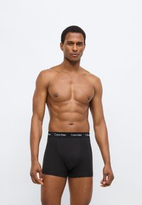 Μαύρα μποξεράκια με μαλακή ζώνη μέσης που φέρει το λογότυπο "Calvin Klein". Λείος υφής, εφαρμοστό σχέδιο και μήκος μέχρι το μέσο του μηρού.