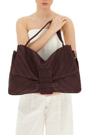 Borsa a mano di un marrone scuro con un motivo trapuntato, forma triangolare oversize, una tracolla piatta e un'illuminante chiusura a tracolla sul davanti.