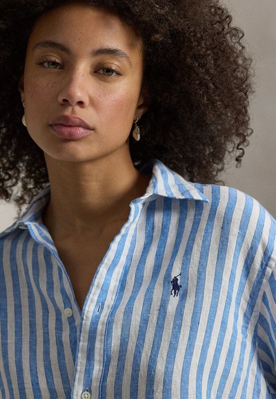 Λινό πουκάμισο με γαλάζιες και λευκές ρίγες, γιακά με κουμπιά κάτω· διαθέτει μικρό ναυτικό λογότυπο στο στήθος· απαλή υφή και άνετη εφαρμογή.