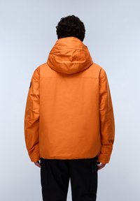 Orange insulated jacket with a hood, featuring a smooth texture and a black patch on the left arm. Pairing with black cargo pants.