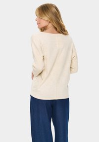 Heledbeez värvi tekstuuriga kerge kootud sviiter, millel on kolmandiku pikkusega varrukad, mugav lõige ja keskmine õmblus seljaosas, koos tumehallide laiadest pükstest.