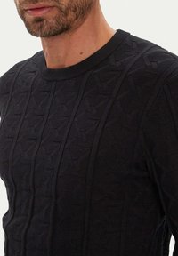 Dunkel gestrickter Pullover mit strukturiertem Muster aus vertikalen Linien. Gerippter Rundhalsausschnitt und figurbetontes Design, gefertigt aus einem weichen Stoff.