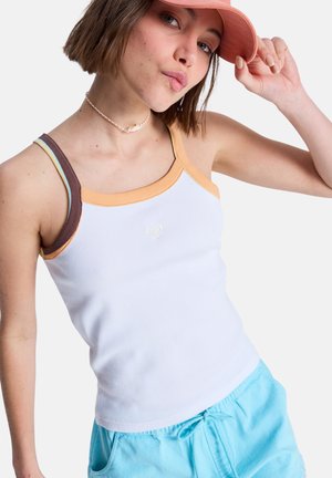 Weißes, geripptes Tanktop mit kontrastierenden orangefarbenen und braunen Trägern. Auf der Brust befindet sich ein kleines Logo, kombiniert mit hellblauen Shorts.