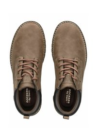 Botines de ante marrón con puntera redonda, tacón oscuro contrastante y cordones beige. Presenta un logo en la plantilla y costura decorativa alrededor de la suela.
